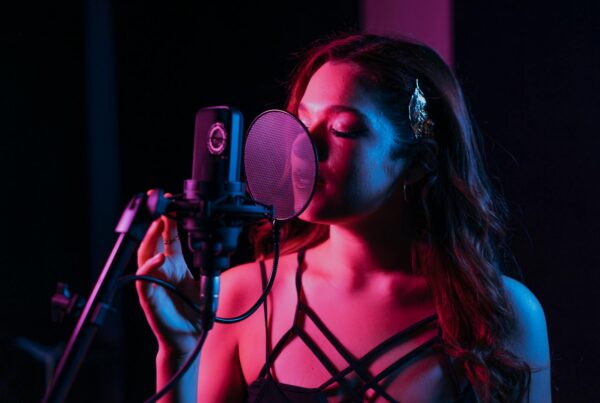 Woman recording vocals in studio with microphone and pop filter