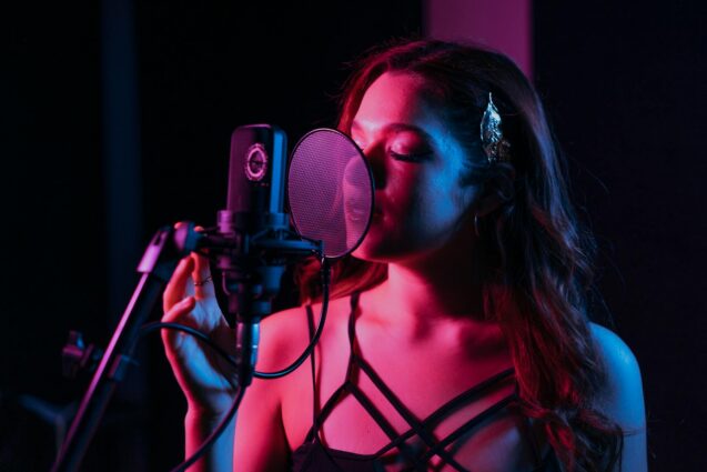 Woman recording vocals in studio with microphone and pop filter
