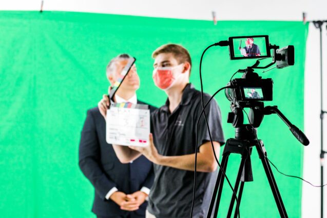 Man with a face mask, about to use the clapperboard