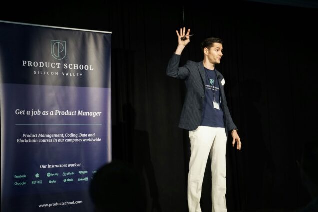 Man raising his hand during a presentation at a conference on stage