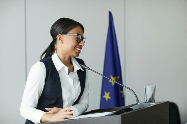 A woman smiling while speaking at the podium