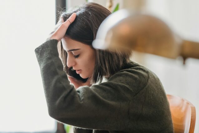 Woman taking a phone call with her hands on her head