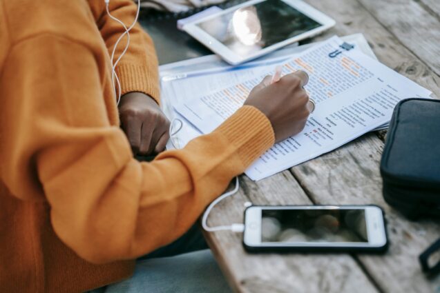 Woman highlighting a printed document while listening to music