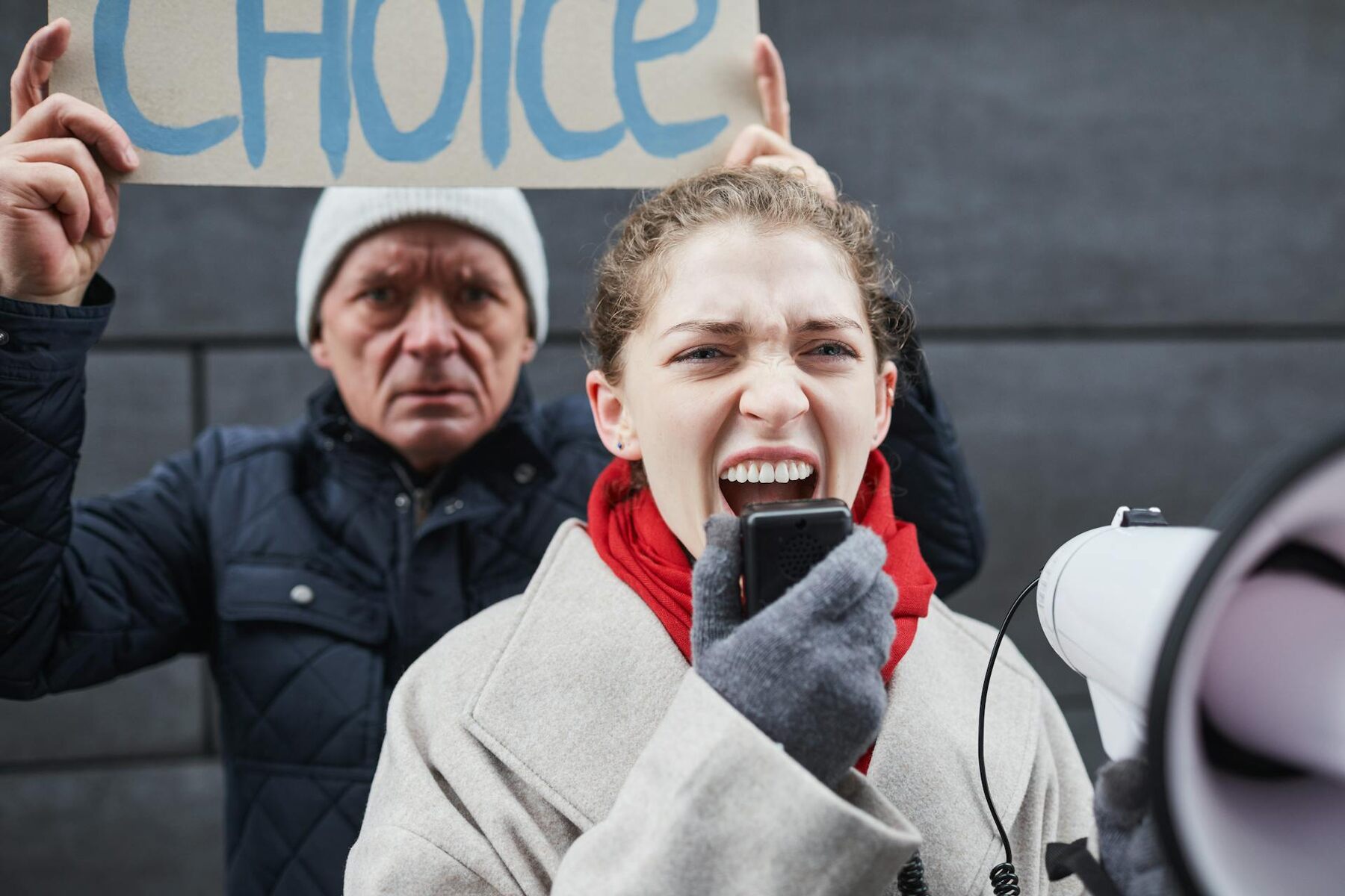 A woman passionately holds a megaphone while a man stands beside her