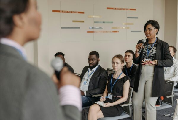 A woman on the audience holding a microphone speaking with a man in front