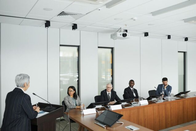 A diverse group of professionals in business attire engaged in discussion around a conference table