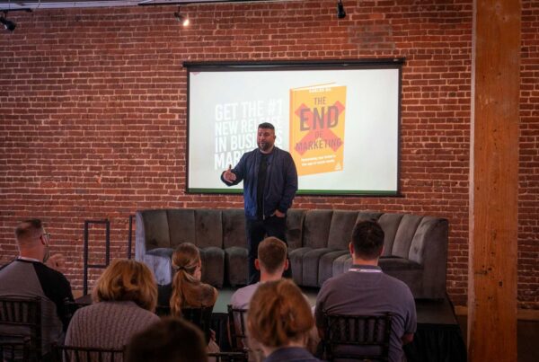 A speaker addresses a captivated audience, standing before a rustic brick wall