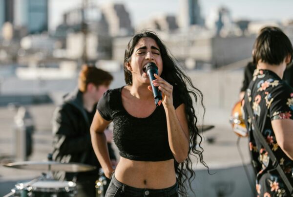 A woman passionately sings into a microphone while standing on a rooftop