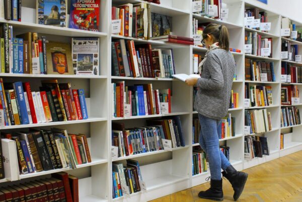 Woman reading a book from a book shelf