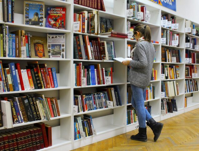 Woman reading a book from a book shelf