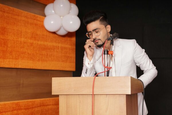 Man with his eyes closed in the middle of his speech in front of a podium