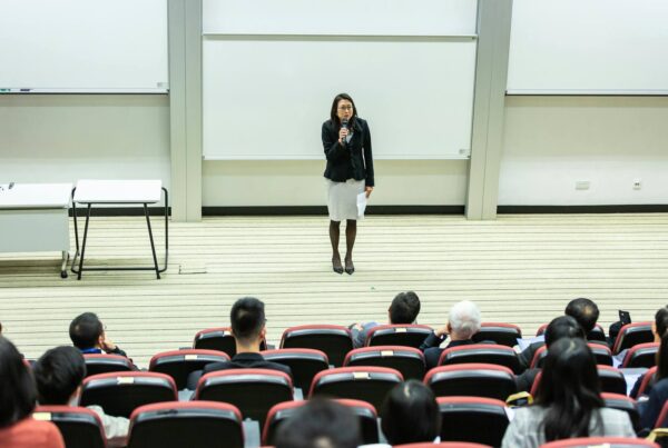 A woman confidently presents to a large audience