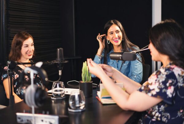 Three women engaged in conversation inside a radio studio