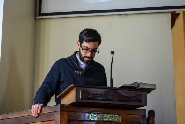 A man with glasses in front of podium with microphone