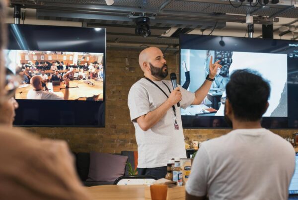 A man presenting to an audience, engaging with the group while using visual aids