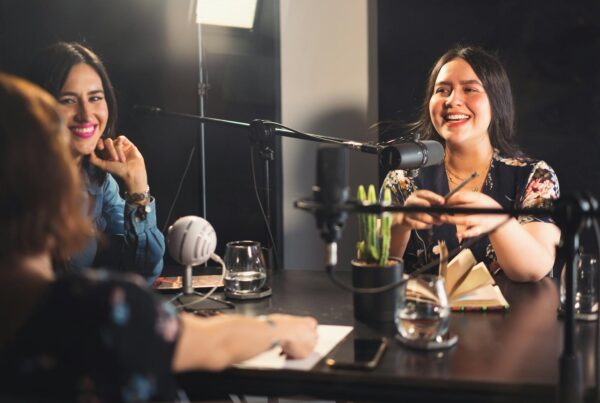 Three women seated at a table, each with a microphone, engaged in discussion