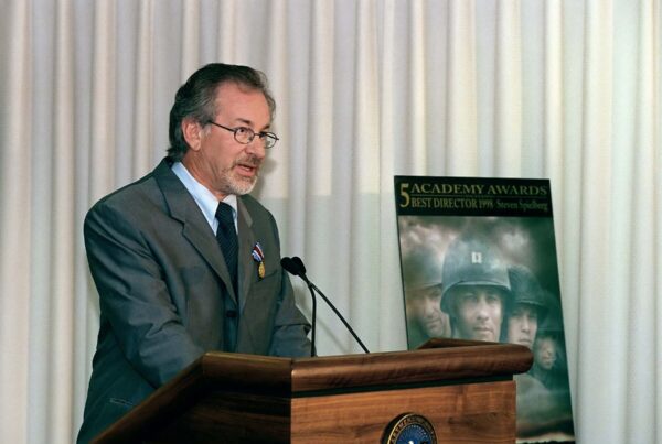 A man in a suit and tie stands confidently at a podium
