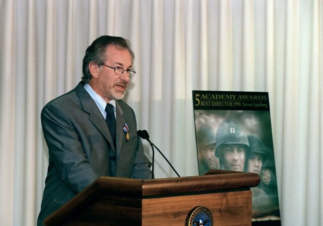 A man in a suit and tie stands confidently at a podium