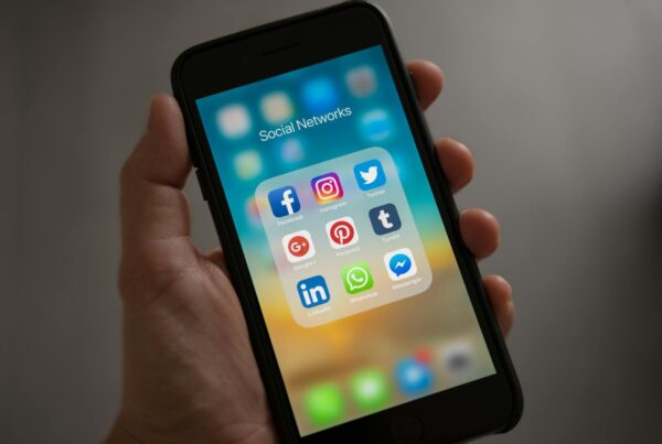 A person holding a mobile phone with social media apps on the screen