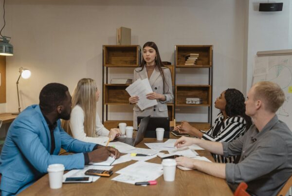 A woman presenting documents to a team at a meeting, with everyone focused on her