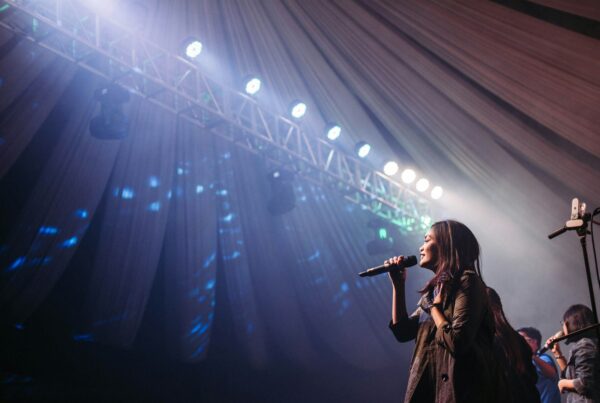 A woman performing on stage, singing to an enthusiastic audience