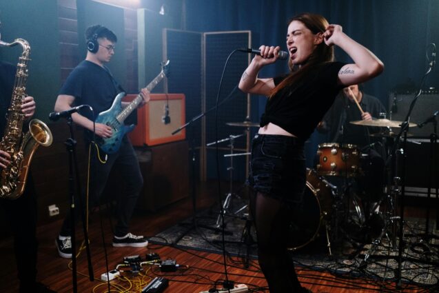A woman singing with her band in a recording studio