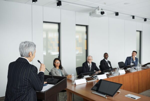 Woman speaking to a panel in a conference room