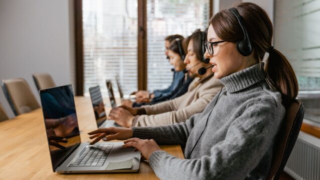Customer service agents wearing headsets while working on laptops